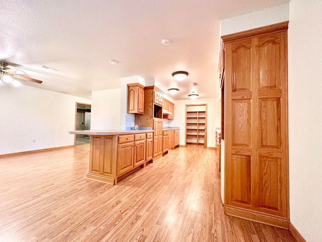 kitchen featuring a textured ceiling, kitchen peninsula, ceiling fan, and light hardwood / wood-style flooring