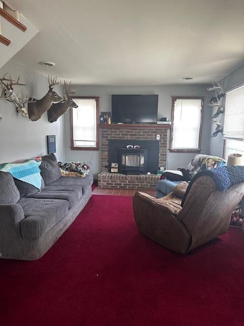 carpeted living room featuring a brick fireplace and a healthy amount of sunlight