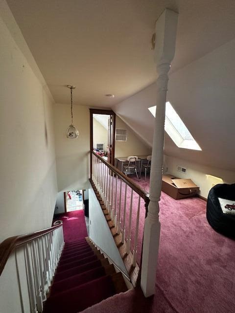 stairs featuring carpet floors, a chandelier, and vaulted ceiling