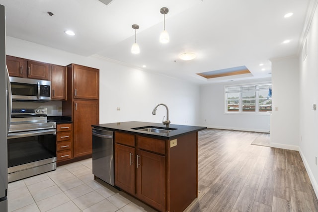 kitchen featuring a kitchen island with sink, stainless steel appliances, sink, light hardwood / wood-style floors, and hanging light fixtures