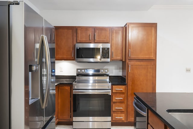 kitchen with stainless steel appliances, dark stone counters, and crown molding