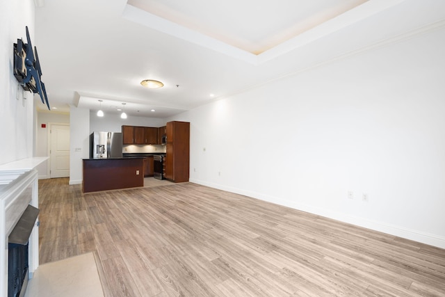 unfurnished living room featuring a raised ceiling, light hardwood / wood-style floors, and ornamental molding