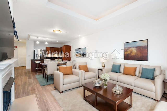 living room with ornamental molding, a tray ceiling, and light hardwood / wood-style floors