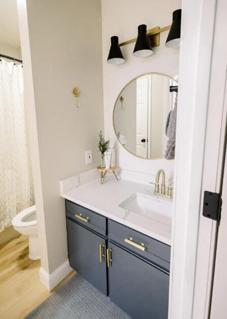 full bath featuring wood finished floors, vanity, curtained shower, baseboards, and toilet