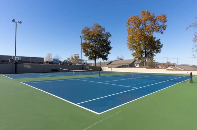 view of tennis court featuring fence and community basketball court