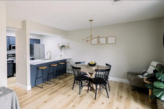 dining space featuring a chandelier, light wood-style floors, visible vents, and baseboards