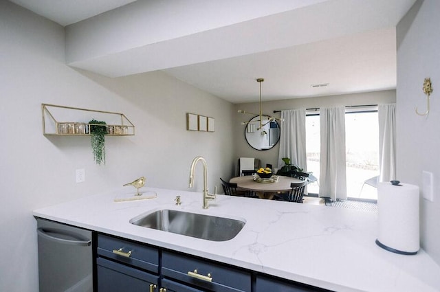 kitchen with blue cabinets, stainless steel dishwasher, a sink, light stone counters, and hanging light fixtures
