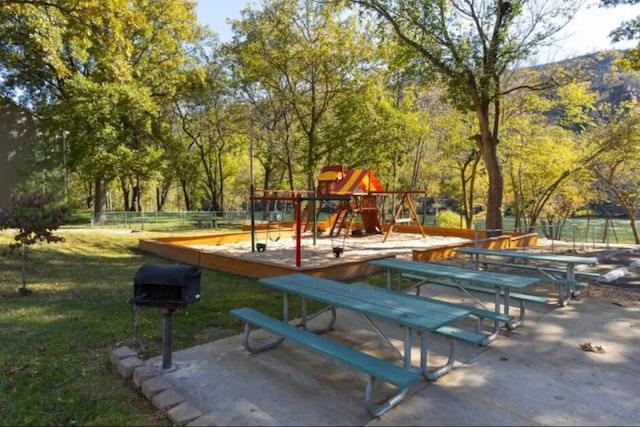view of property's community featuring playground community, fence, and a yard