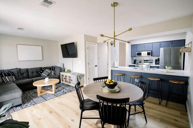 dining room featuring sink, an inviting chandelier, and light hardwood / wood-style flooring