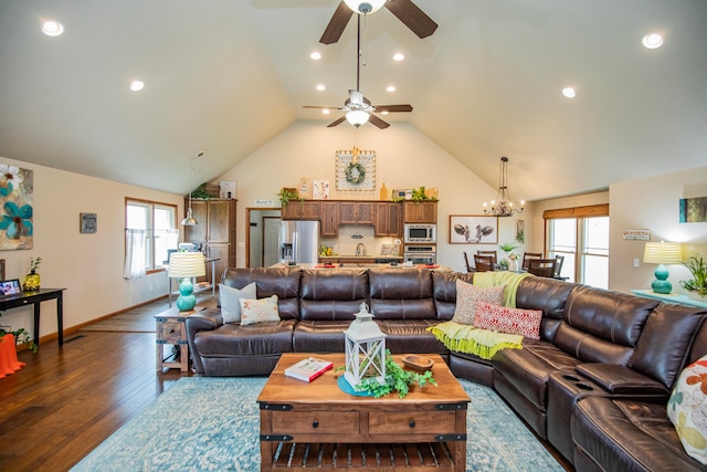 living room with dark wood-type flooring, ceiling fan with notable chandelier, and vaulted ceiling