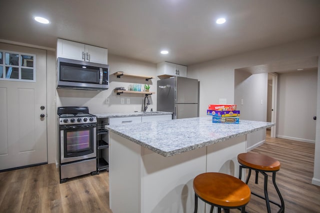 kitchen with white cabinetry, light hardwood / wood-style floors, appliances with stainless steel finishes, and a kitchen breakfast bar