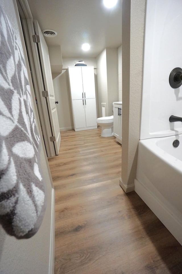 bathroom featuring wood-type flooring, shower with separate bathtub, and toilet