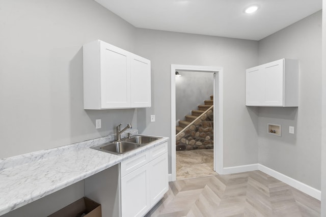 kitchen with white cabinetry, light parquet flooring, sink, and light stone counters