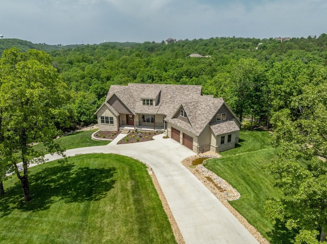 653 Forest Lake Dr, Branson West, MO 65737 - view of front of house featuring a wooded view, stone siding, concrete driveway, a garage, and a front lawn