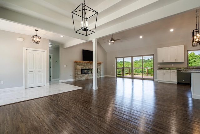 653 Forest Lake Dr, Branson West, MO 65737 - unfurnished living room featuring a chandelier, ceiling fan, baseboards, a stone fireplace, and high vaulted ceiling