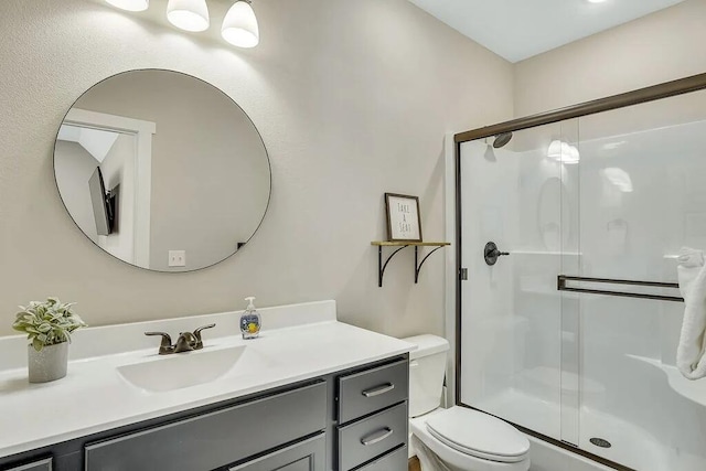 bathroom featuring vanity, a shower with shower door, and toilet