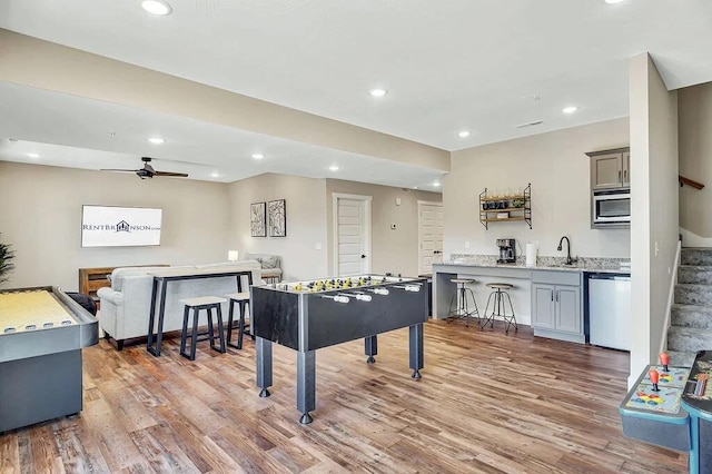 rec room with ceiling fan, light hardwood / wood-style flooring, and sink