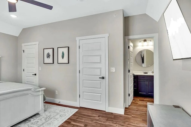 bedroom featuring ceiling fan, ensuite bath, hardwood / wood-style floors, and vaulted ceiling