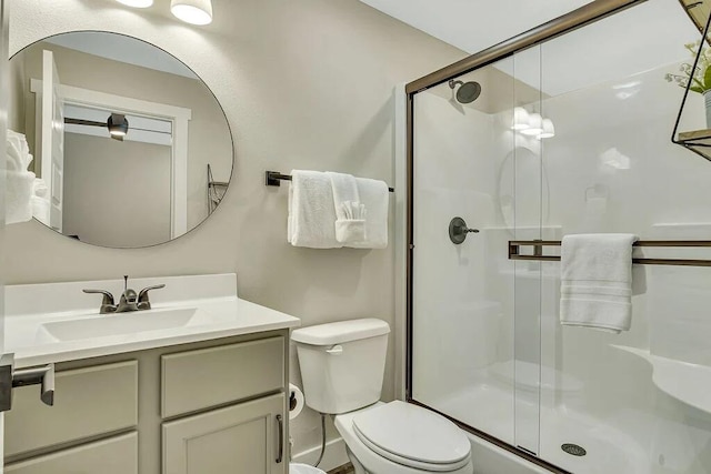 bathroom with an enclosed shower, vanity, and toilet