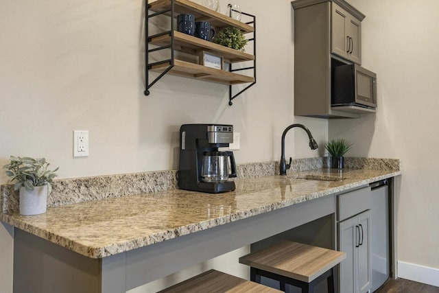 kitchen featuring light stone counters, dark hardwood / wood-style floors, sink, and gray cabinetry