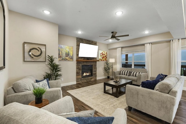 living room with a fireplace, dark wood-type flooring, and ceiling fan