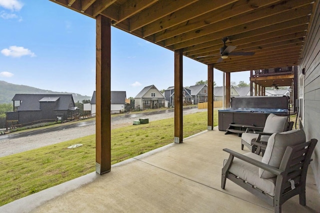 view of patio / terrace with ceiling fan, a mountain view, and a hot tub