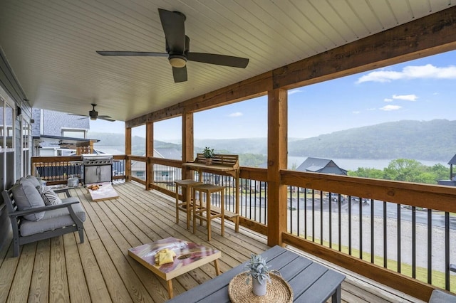 wooden deck with ceiling fan and a water and mountain view