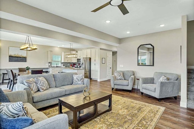 living room with wood-type flooring and ceiling fan with notable chandelier