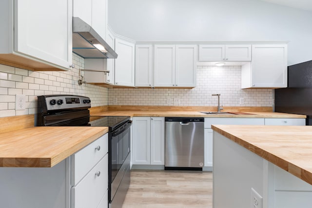 kitchen featuring stainless steel appliances, white cabinets, wooden counters, wall chimney exhaust hood, and sink