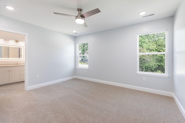 empty room with a healthy amount of sunlight, ceiling fan, sink, and light colored carpet