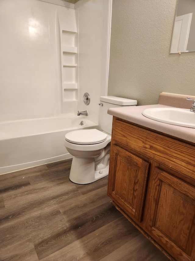 full bathroom with washtub / shower combination, hardwood / wood-style floors, vanity, and toilet