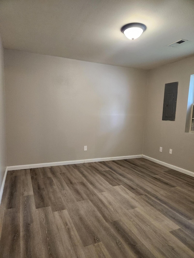 spare room featuring electric panel and dark hardwood / wood-style flooring