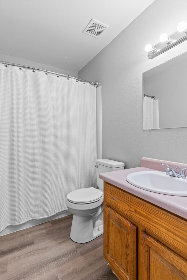 bathroom featuring wood-type flooring, a shower with curtain, vanity, and toilet