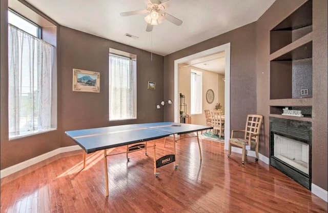 rec room featuring wood-type flooring, ceiling fan, and a healthy amount of sunlight