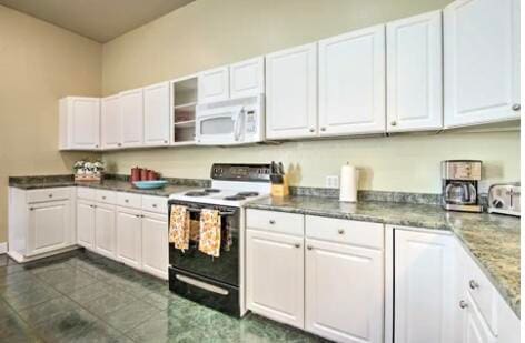 kitchen with dark tile patterned flooring, black range with electric cooktop, and white cabinetry