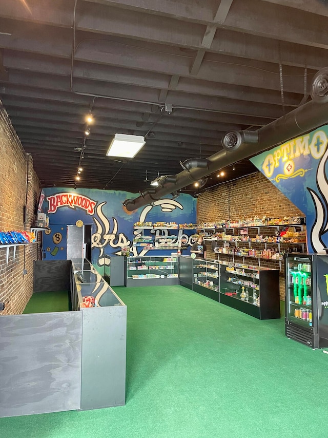 game room featuring carpet floors, rail lighting, and brick wall