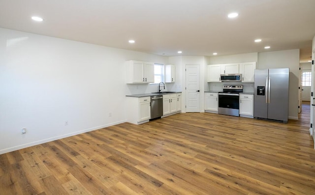 kitchen featuring appliances with stainless steel finishes, light wood-type flooring, white cabinetry, and a healthy amount of sunlight