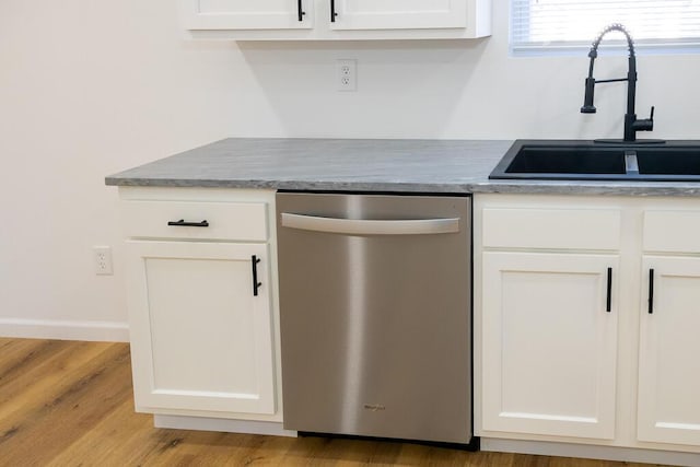 kitchen featuring stainless steel dishwasher, white cabinetry, sink, and light hardwood / wood-style flooring