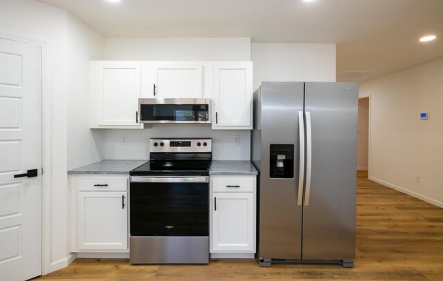 kitchen featuring white cabinets, light wood-type flooring, and stainless steel appliances