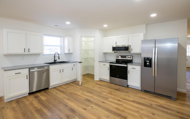 kitchen featuring white cabinetry, sink, stainless steel appliances, and light wood-type flooring