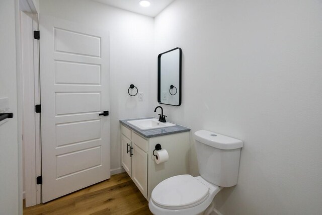 bathroom featuring vanity, hardwood / wood-style flooring, and toilet