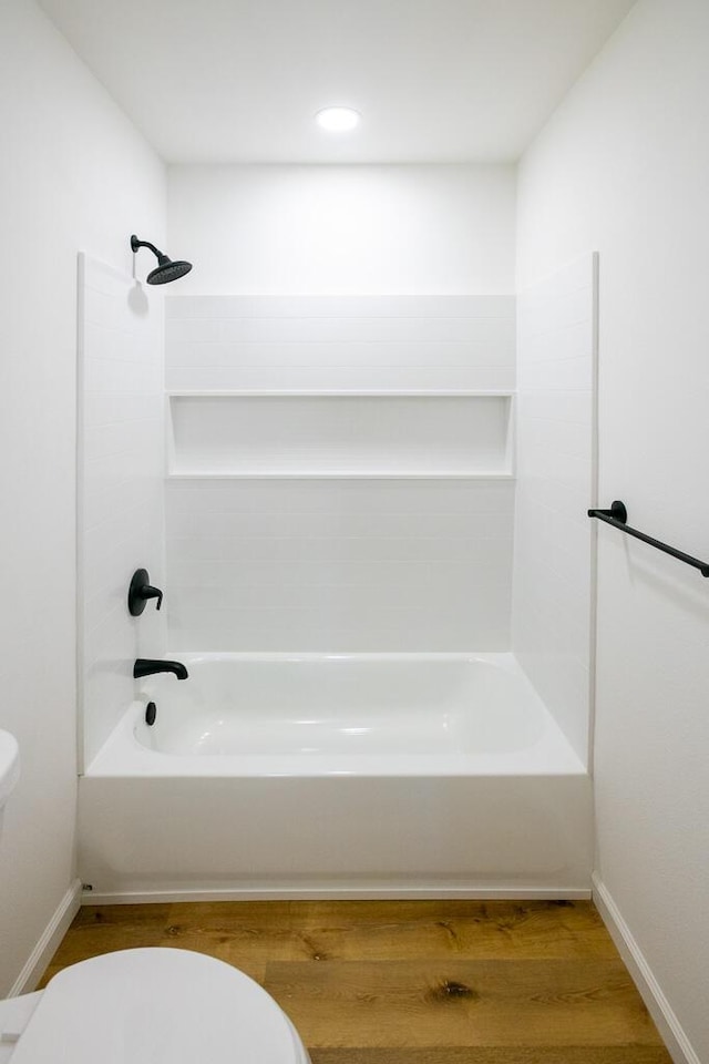 bathroom with wood-type flooring,  shower combination, and toilet