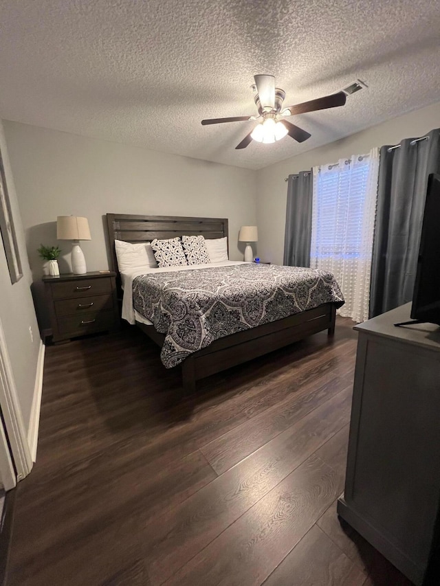 bedroom with ceiling fan, dark hardwood / wood-style floors, and a textured ceiling