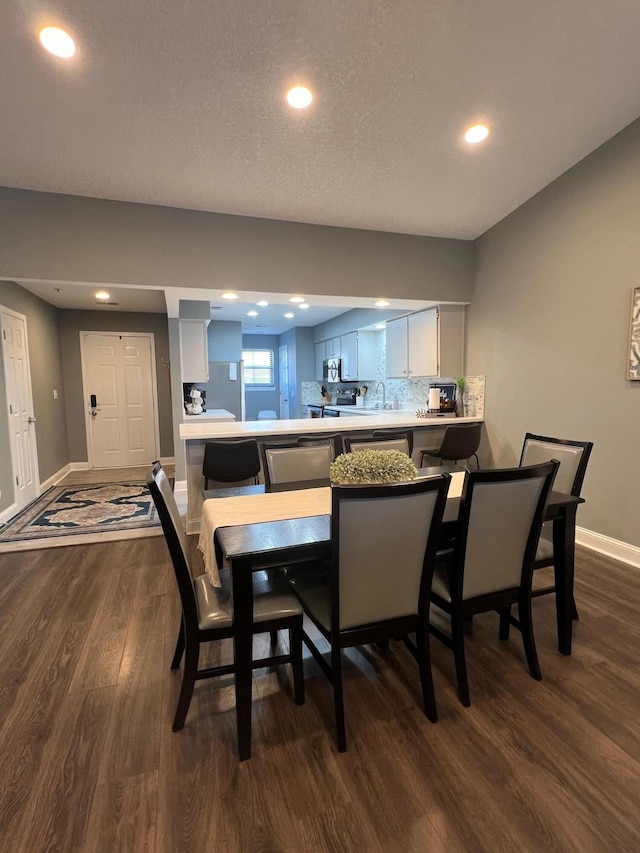 dining area featuring a textured ceiling, sink, and dark hardwood / wood-style flooring