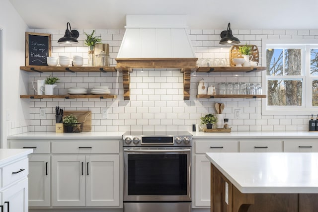 kitchen with tasteful backsplash, white cabinetry, custom range hood, and stainless steel electric stove