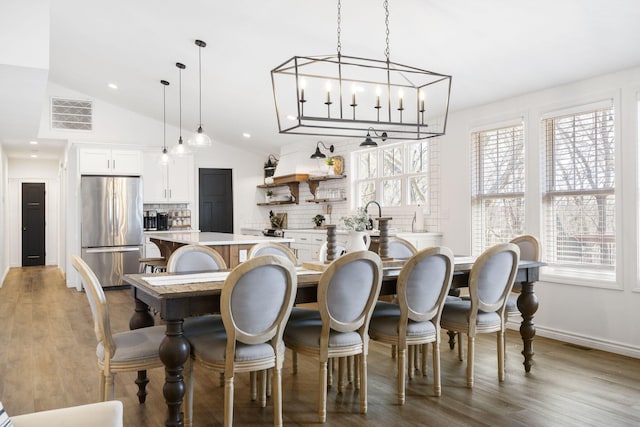 interior space with a notable chandelier, lofted ceiling, plenty of natural light, and hardwood / wood-style flooring