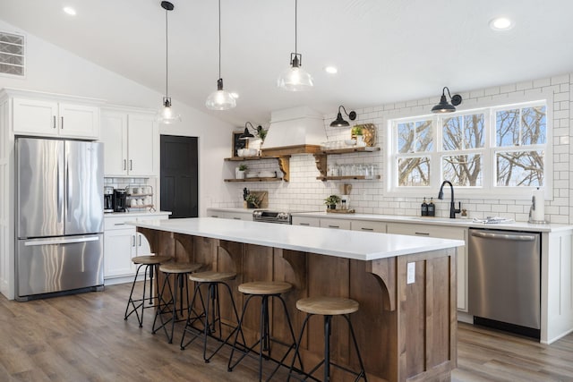 kitchen featuring lofted ceiling, white cabinetry, stainless steel appliances, a center island, and dark hardwood / wood-style flooring