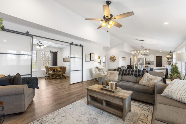 living room with a barn door, wood-type flooring, ceiling fan with notable chandelier, and lofted ceiling