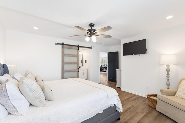 bedroom featuring ceiling fan, a barn door, and hardwood / wood-style floors