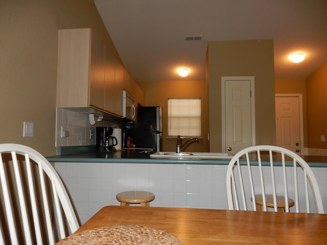 kitchen featuring tasteful backsplash, stainless steel fridge, and sink